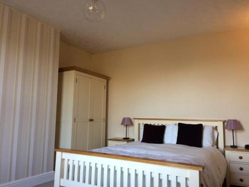 a bedroom with a white bed with black pillows at Halfway House in Great Malvern