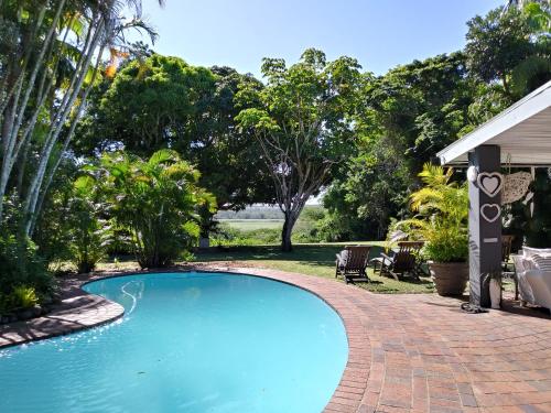 a swimming pool with a brick walkway next to a yard at St Lucia Kingfisher Lodge in St Lucia