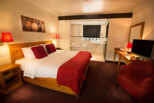 a hotel room with a bed and a desk and a television at Guy's Thatched Hamlet in Barton