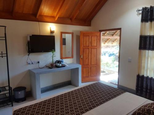 a bedroom with a bed and a tv on the wall at Inn On The Bay in Pasikuda