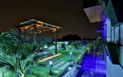 un jardín iluminado por la noche con luces púrpuras en Hotel D'PRESIDENTE, en Nueva Delhi