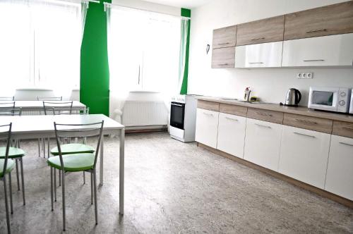 a kitchen with white cabinets and a table and chairs at Penzion První Liga in Hradec Králové
