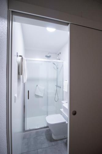 a bathroom with a toilet and a glass shower at Hostal Pensimar in El Altet