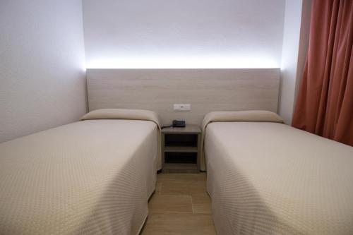 two beds in a small room with a table at Hostal Pensimar in El Altet