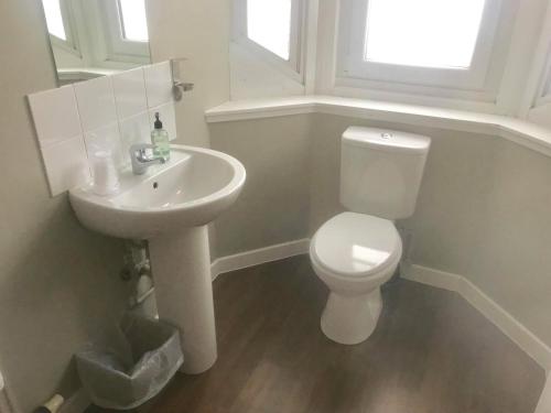 a white bathroom with a toilet and a sink at Chieftain Hotel in Inverness