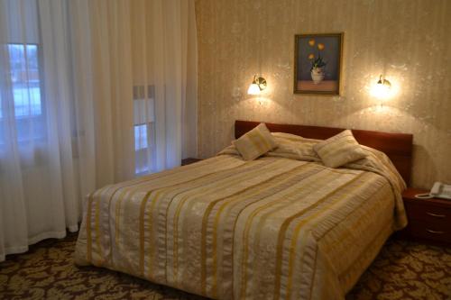 een slaapkamer met een bed met een gestreepte deken en een raam bij Gilija in Šilutė