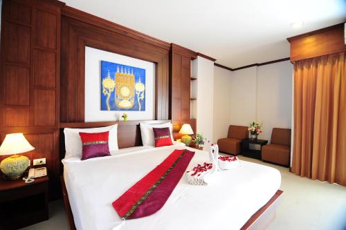 1 dormitorio con 1 cama blanca grande con almohadas rojas en Arita Hotel Patong, en Patong Beach