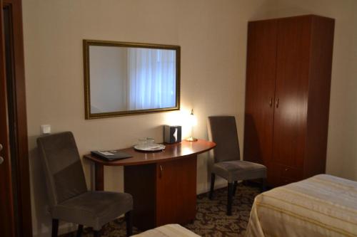 a hotel room with a desk and a bed and a mirror at Gilija in Šilutė