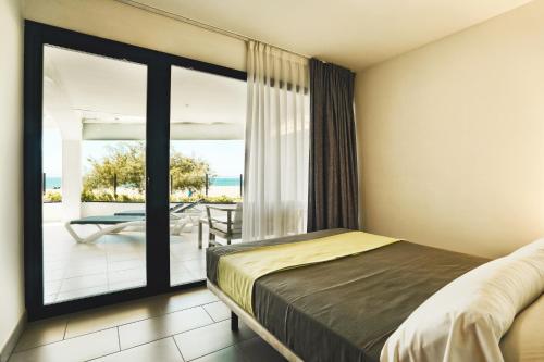a bedroom with a bed and a balcony with a table at Pins Platja Apartments in Cambrils