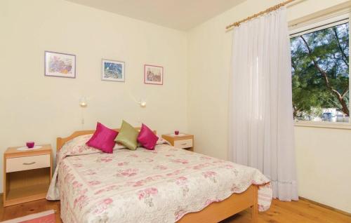 a bedroom with a bed with pink pillows and a window at Okuklje Holiday Home in Okuklje