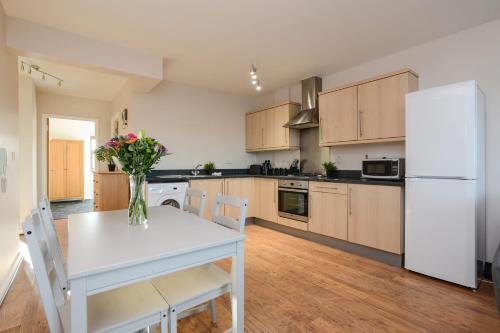 uma cozinha com uma mesa branca e um frigorífico branco em Portland Square - 2 Bedroom Modern City Apartment em Nottingham