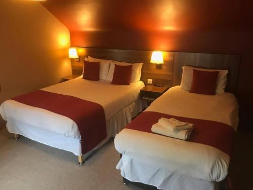 a hotel room with two beds and two lamps at Chieftain Hotel in Inverness