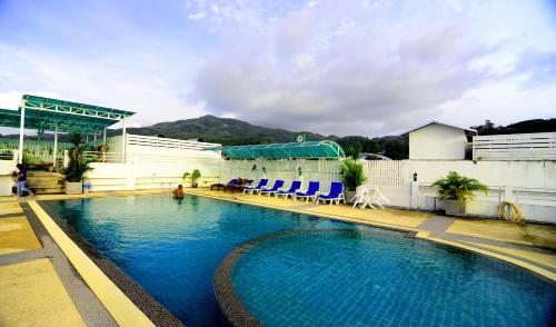 a large swimming pool with blue chairs in front of a building at Arita Hotel Patong in Patong Beach