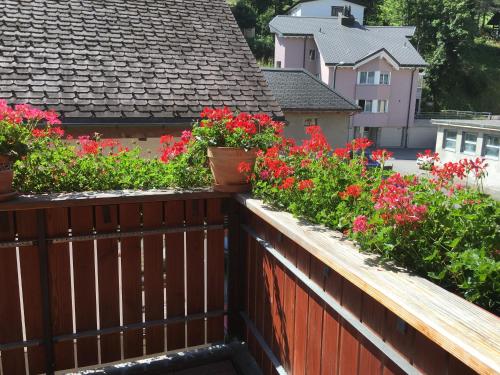 a wooden fence with flowers on a balcony at Privatzimmer / bed & breakfast in Andermatt
