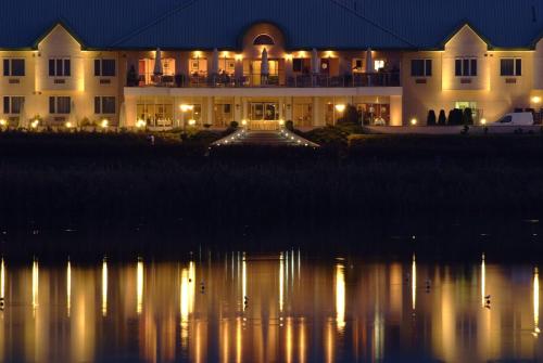 a large building with lights on the water at night at Hotel HP Park Poznań Malta in Poznań