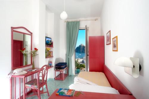 a bedroom with a bed and a desk and a window at Hotel Ulisse in Ischia