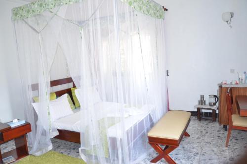 a bedroom with a bed with curtains and a chair at Sheevy"s Bed N Breakfast in Fort Portal