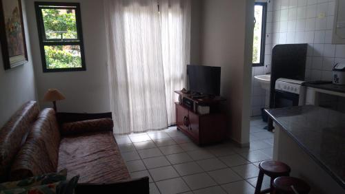 a living room with a couch and a television at Apartamento em Ubatuba próximo a praia! in Ubatuba