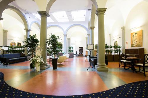 a large lobby with columns and tables and chairs at Relais Hotel Centrale "Dimora Storica" in Florence