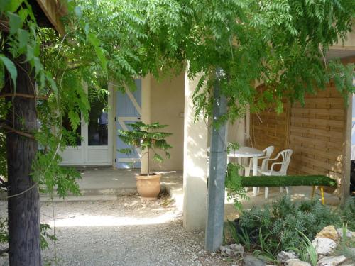 un jardín con una mesa, un banco y una puerta en Leucateloc, en Leucate-Plage