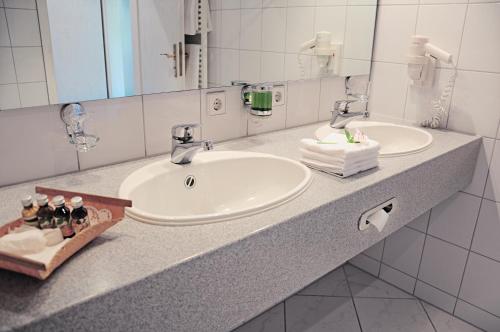 Baño con 2 lavabos y espejo en Hotel Krone Überlingen am Ried, en Singen