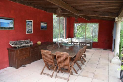 comedor con paredes rojas y mesa y sillas de madera en Les Gîtes Les Mayombes, en Roquebrune-sur-Argens
