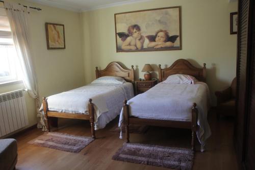 um quarto com duas camas e um quadro na parede em Quartos em vivenda serra da Estrela em Celorico da Beira