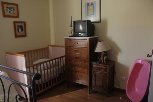 a room with a crib and a tv on a dresser at Quartos em vivenda serra da Estrela in Celorico da Beira