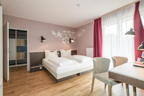 um quarto com uma cama branca, uma mesa e cadeiras em JUFA Hotel Königswinter/Bonn em Königswinter