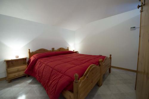 a bedroom with a wooden bed with a red bedspread at Mansarda plein soleil in Donnaz