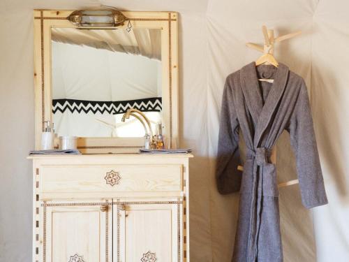a coat on a hanger next to a mirror at Nubia Luxury Camp Erg Chegaga in El Gouera