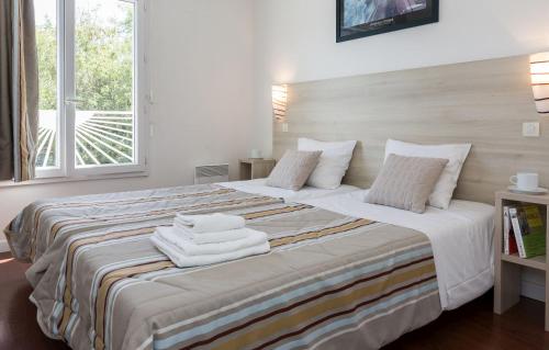 - une chambre avec un grand lit et des serviettes dans l'établissement Résidence Odalys Thalassa, à Les Sables-dʼOlonne