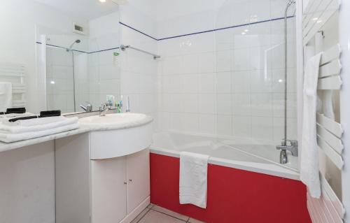La salle de bains est pourvue d'une baignoire rouge et blanche ainsi que d'un lavabo. dans l'établissement Résidence Odalys Thalassa, à Les Sables-dʼOlonne