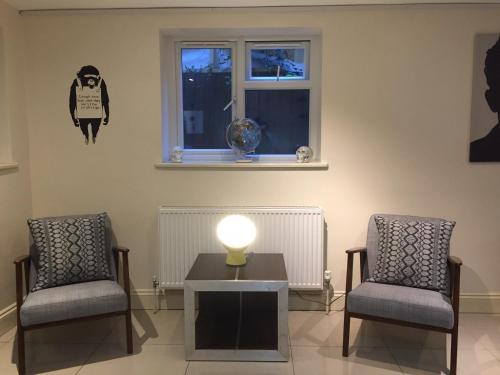 a room with two chairs and a table and a window at Mapesbury Hostel London in London
