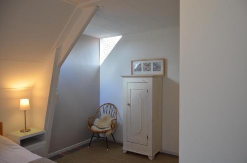 a bedroom with a bed and a chair and a window at Hotel De Waag in Bergen