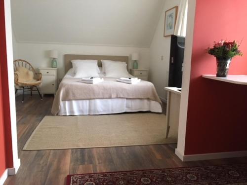 a bedroom with a white bed and a red wall at Hotel De Waag in Bergen