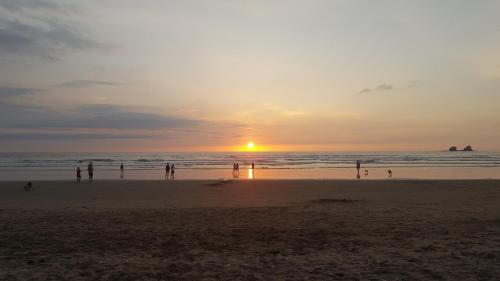 a group of people on the beach at sunset at Las Cabañas de la Iguana in Ayampe