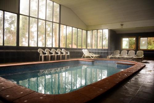 - une piscine avec des chaises dans une chambre dotée de fenêtres dans l'établissement Hotel Borde Lago, à Puerto Varas