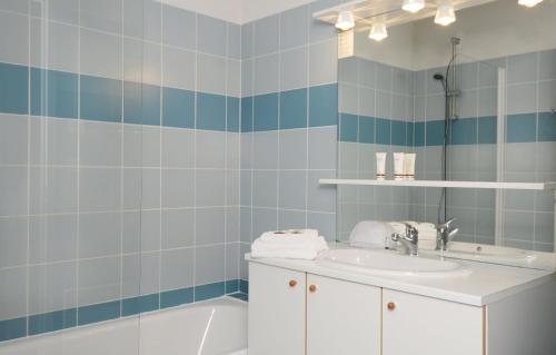 La salle de bains est pourvue d'un lavabo, d'une baignoire et d'un miroir. dans l'établissement Résidence Odalys Le Hameau du Lac, à Rignac