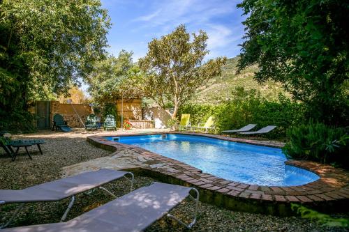 einen Pool in einem Garten mit zwei Liegestühlen in der Unterkunft Casa Rural la Casa del Bosque in Navaconcejo