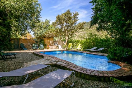 a swimming pool in a yard with two lounge chairs at Casa Rural la Casa del Bosque in Navaconcejo