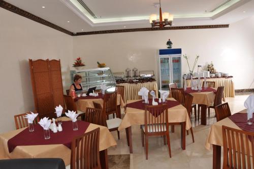 a woman sitting at a table in a restaurant at Akas-Inn Hotel Apartment in Dubai