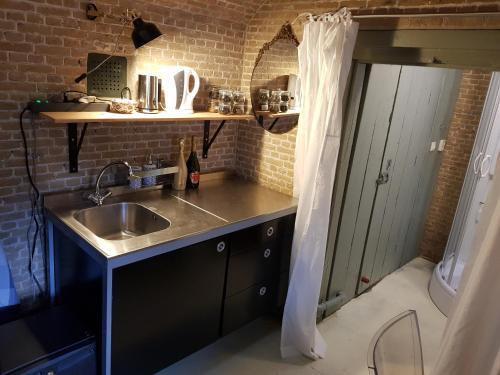a kitchen with a sink and a brick wall at Kazemat Zus in Woudrichem