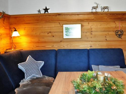 a living room with a blue couch and a wooden wall at Gästehäuser Schwemmbauer in Reit im Winkl