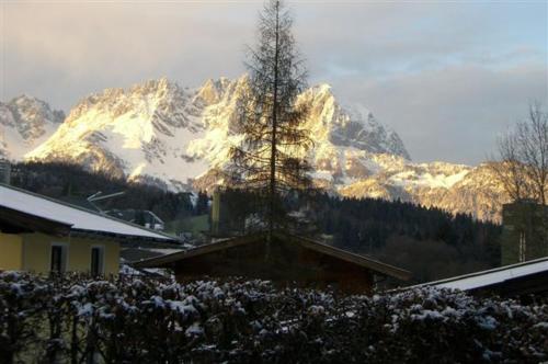 a snow covered mountain in front of a house at Ferienwohnung Reiner in Oberndorf in Tirol