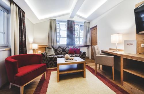 a living room with a couch and a red chair at Familien- und Wellnesshotel Hanneshof in Kleinarl
