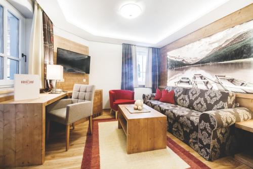 a living room with a couch and a table at Familien- und Wellnesshotel Hanneshof in Kleinarl