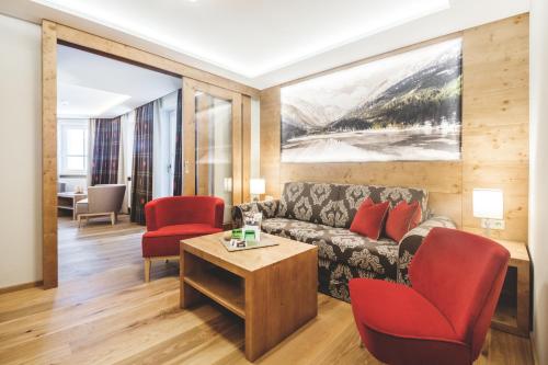a living room with a couch and red chairs at Familien- und Wellnesshotel Hanneshof in Kleinarl