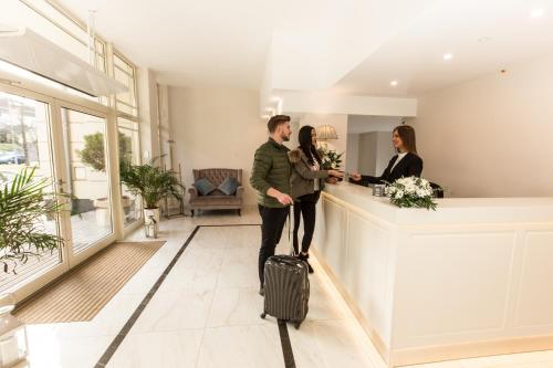 mężczyzna i kobieta z walizką w holu hotelowym w obiekcie Villa Bravo & SPA w mieście Międzyzdroje