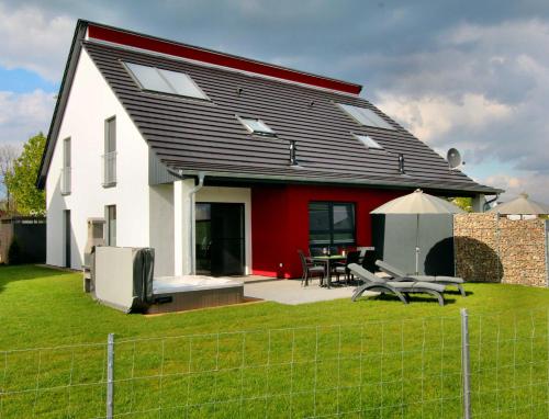 a red and white house with a table and chairs at Ferien_HAUS LIMERICK in Göhren-Lebbin